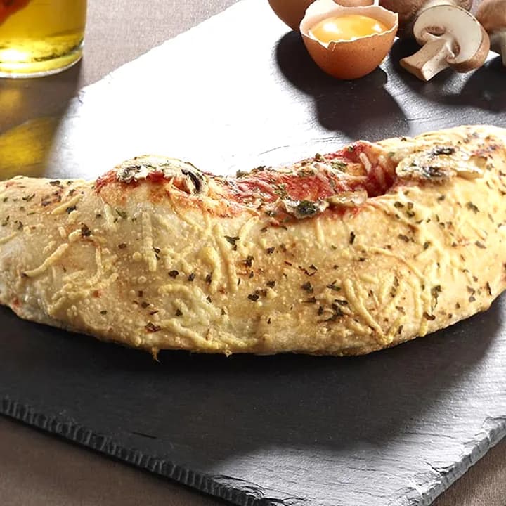 Pizza Calzone : Jambon blanc, Champignons, Emmental, Mozzarella, Jaune d'œuf, Origan, Olives